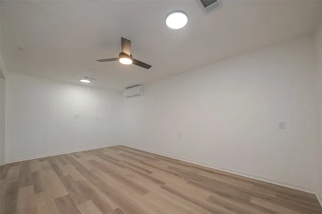 en empty room with wooden floor and ceiling fan
