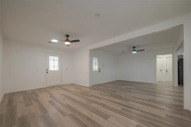 an empty room with wooden floor and windows