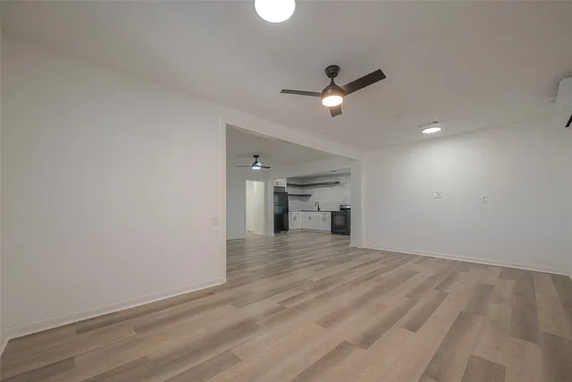 an empty room with wooden floor ceiling fan and windows