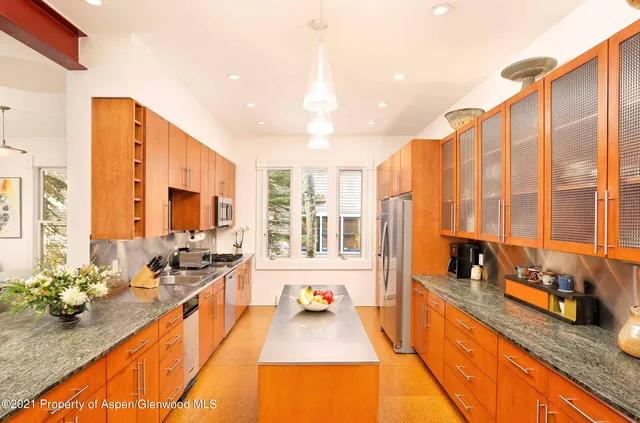 a large kitchen with kitchen island granite countertop a large counter top stainless steel appliances and a large window