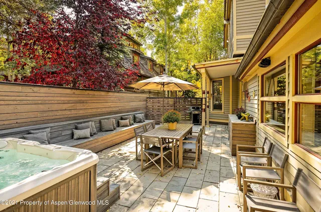 a view of a patio with a table and chairs under an umbrella with a small yard