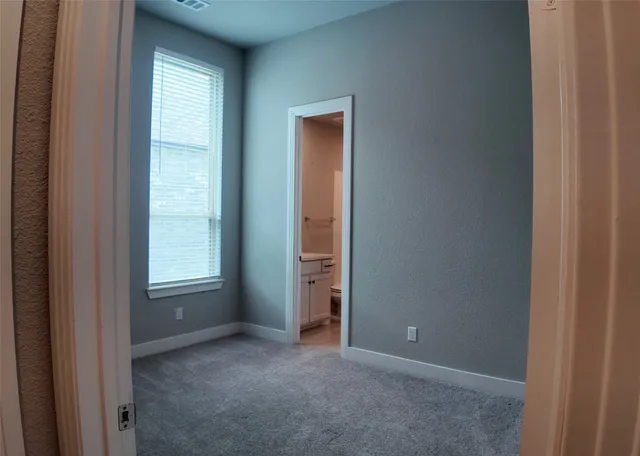 a view of an empty room with closet and a window