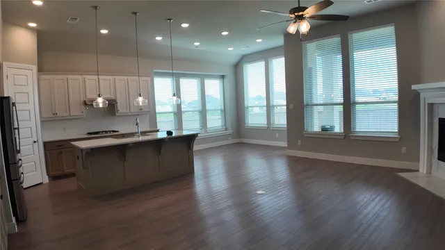 a open kitchen with stainless steel appliances granite countertop a refrigerator a stove and a wooden floors