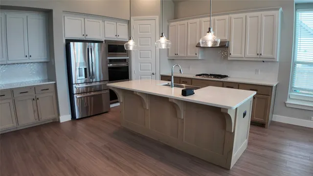 a kitchen with stainless steel appliances a sink cabinets and wooden floor
