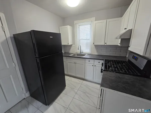 a kitchen with a refrigerator and white cabinets