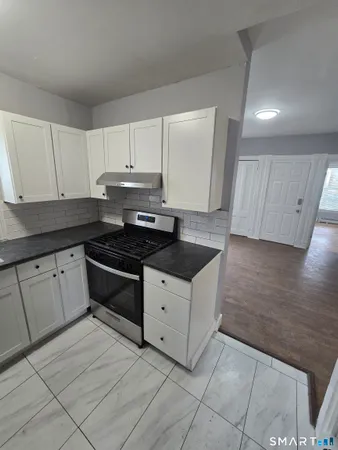 a kitchen with granite countertop white cabinets and black appliances