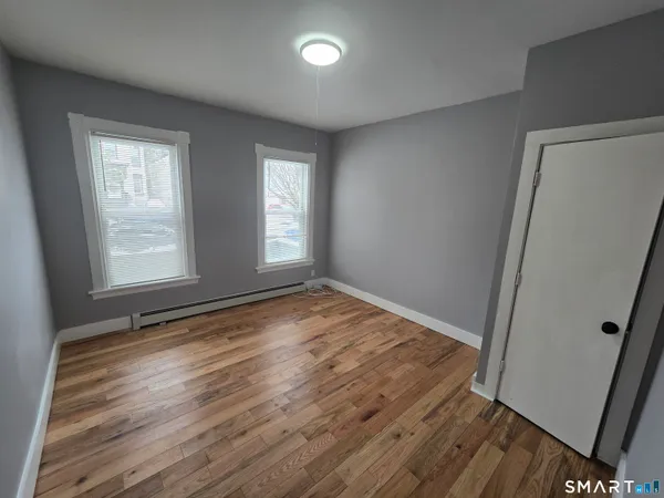 an empty room with wooden floor and windows