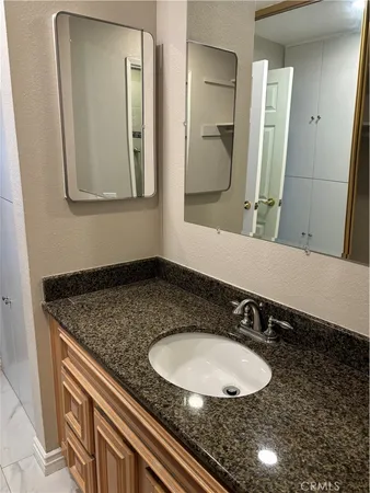 a bathroom with a granite countertop sink and a mirror