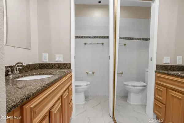 a bathroom with a granite countertop sink toilet and shower