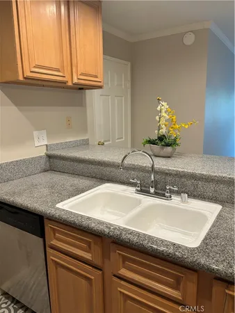 a sink with a granite countertop white cabinets and a sink
