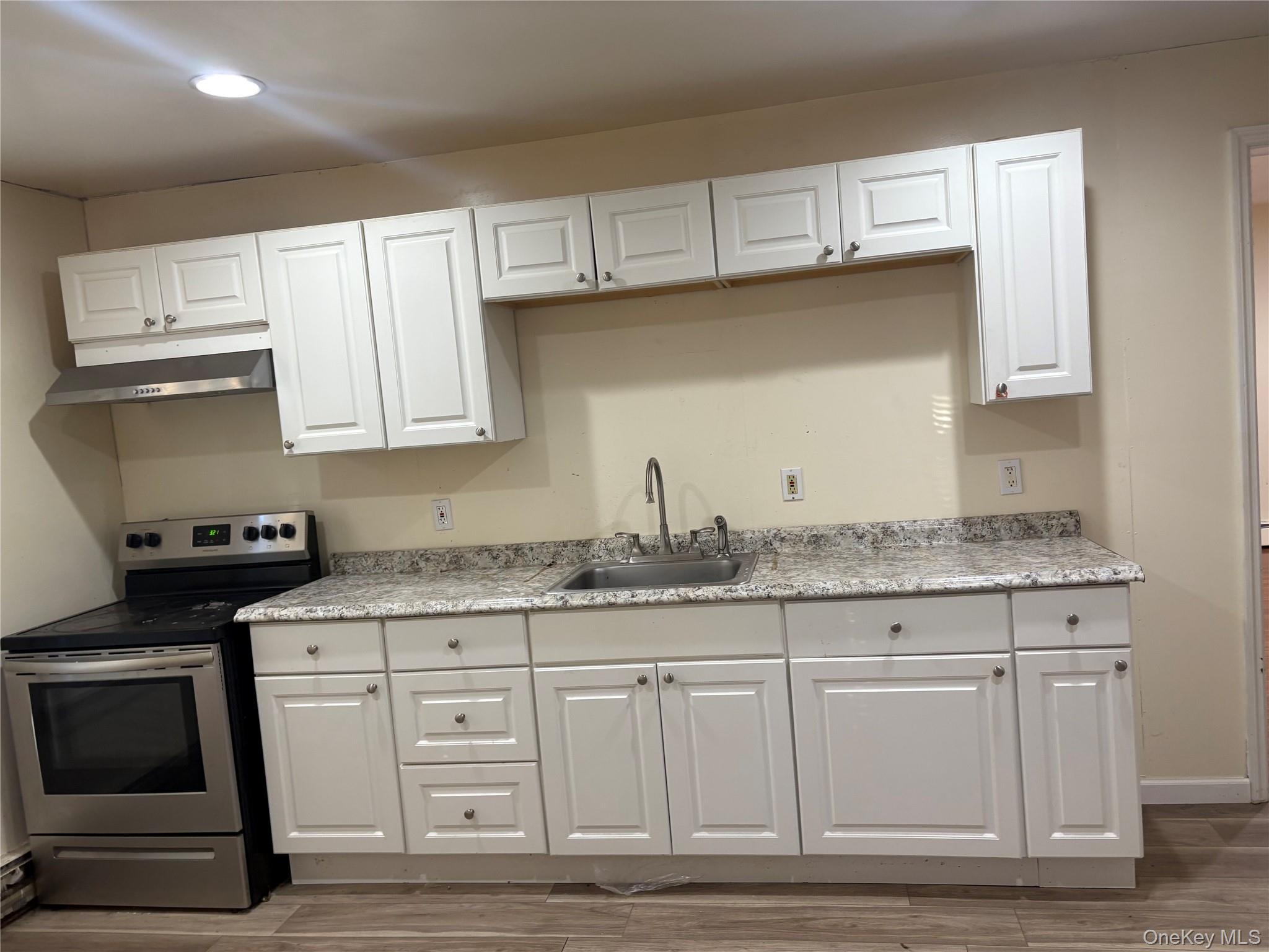 a kitchen with granite countertop white cabinets and a stove