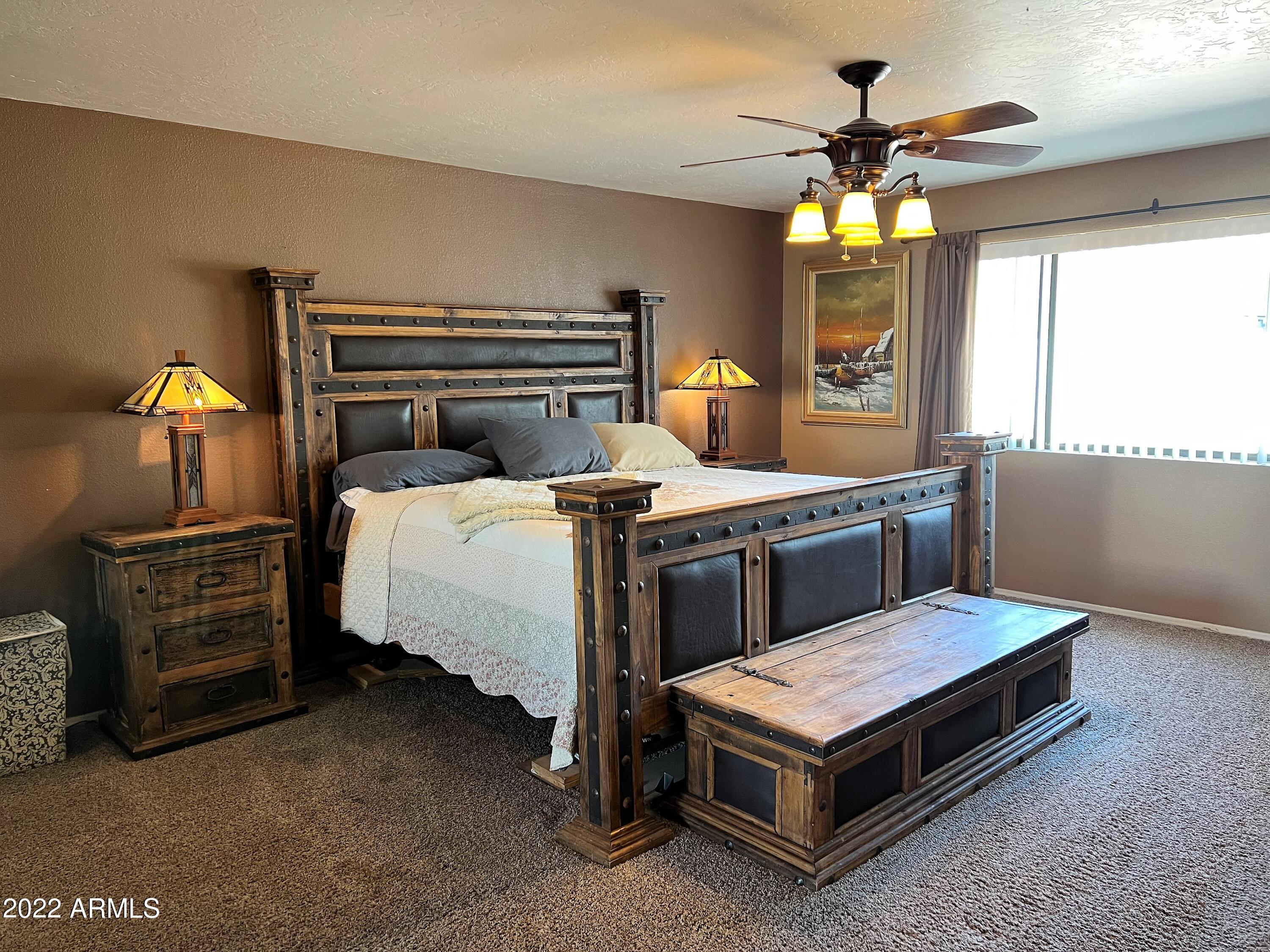 16502 West Magnolia Street Goodyear, AZ 85338 - Photo 20 of 59 a bedroom with a bed and a chandelier