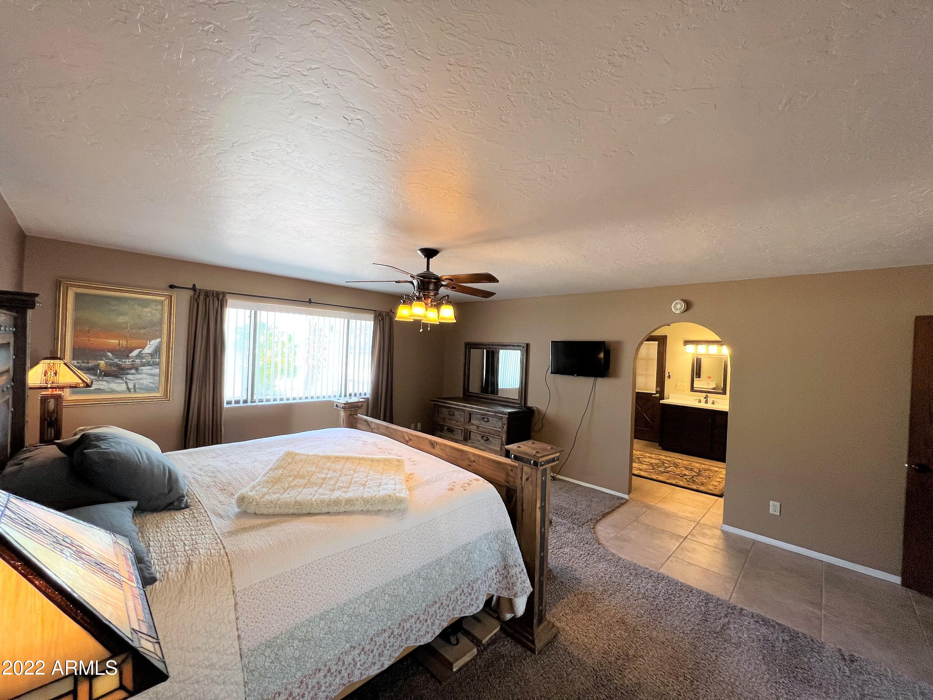 16502 West Magnolia Street Goodyear, AZ 85338 - Photo 22 of 59 a bedroom with a bed and a chandelier