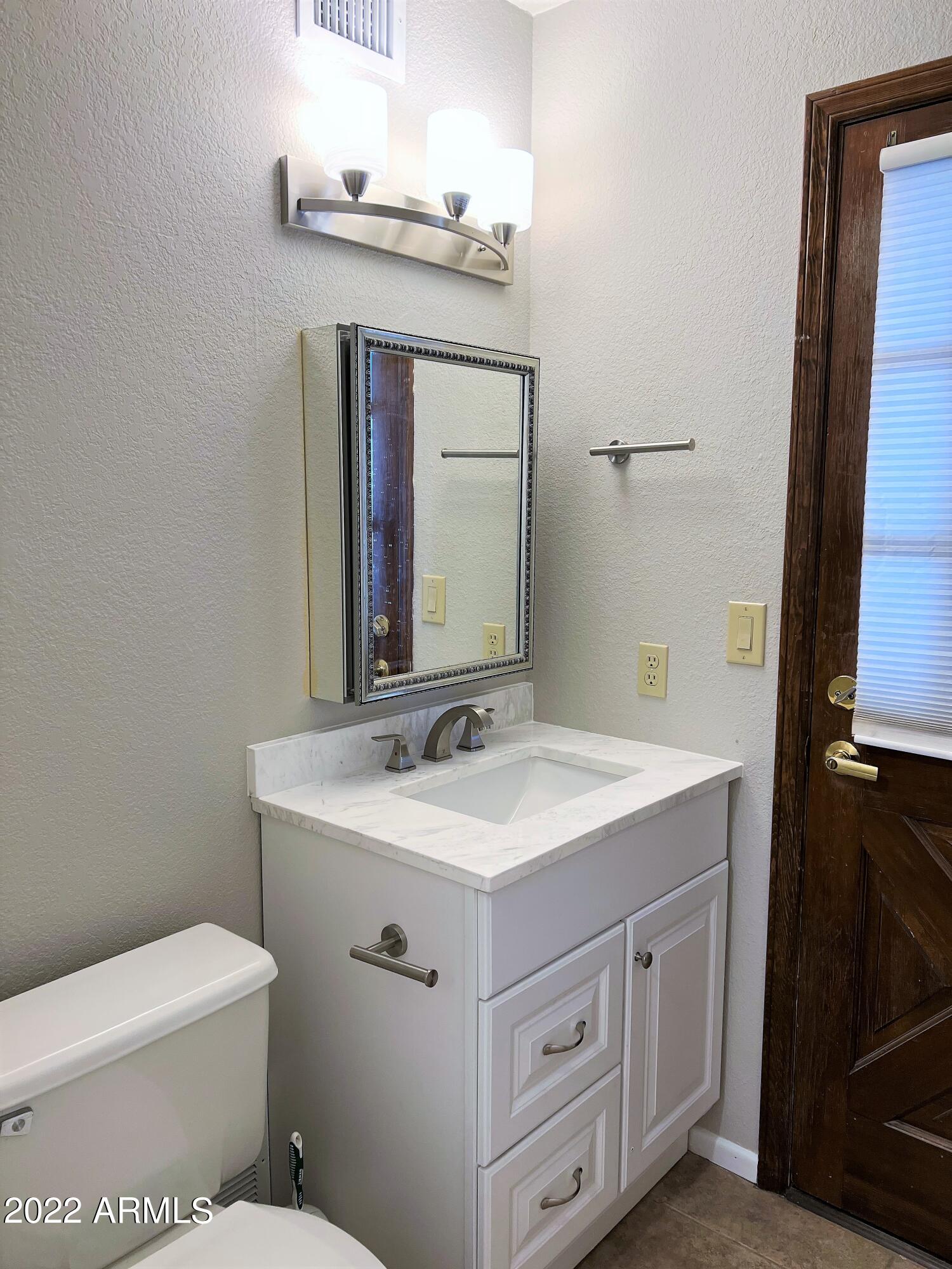 16502 West Magnolia Street Goodyear, AZ 85338 - Photo 31 of 59 a bathroom with a toilet sink and mirror