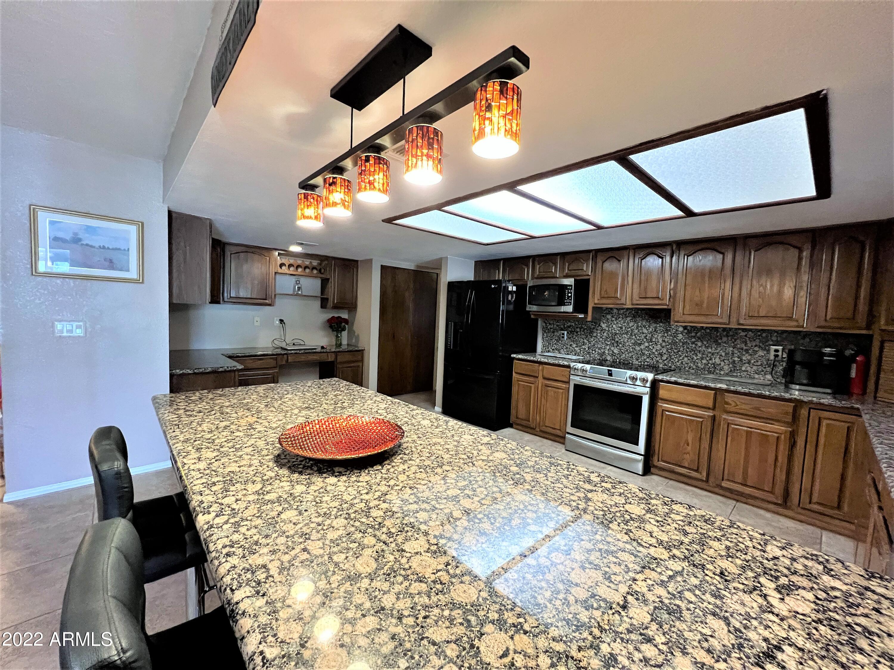 16502 West Magnolia Street Goodyear, AZ 85338 - Photo 5 of 59 a kitchen with stainless steel appliances granite countertop a sink and cabinets