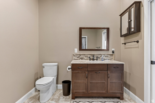 3311 West Allard Summit, UT 84772 - Photo 78 of 97 Powder room featuring a dark wood vanity with a light-toned countertop, a rectangular framed mirror, and a mosaic tile backsplash