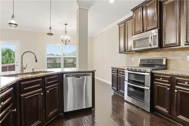 a kitchen with stainless steel appliances granite countertop a stove a sink and a microwave
