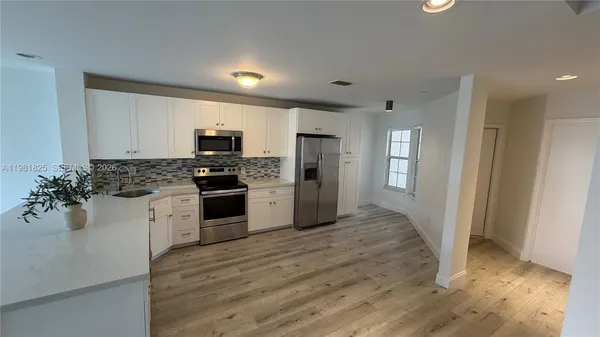 a kitchen with granite countertop white cabinets and stainless steel appliances