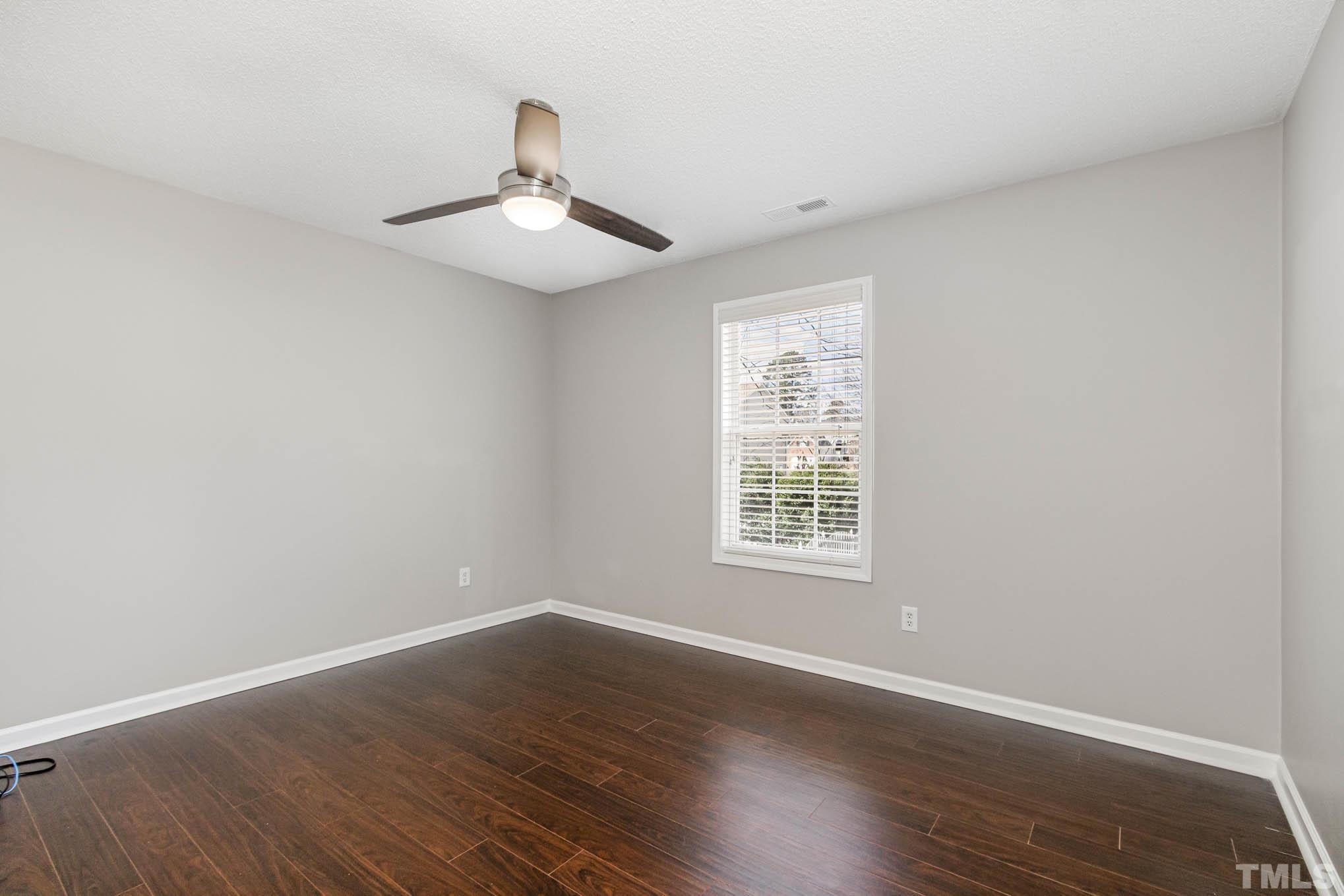 266 Inkster Cove Raleigh, NC 27603 - Photo 23 of 30 an empty room with wooden floor ceiling fan and windows