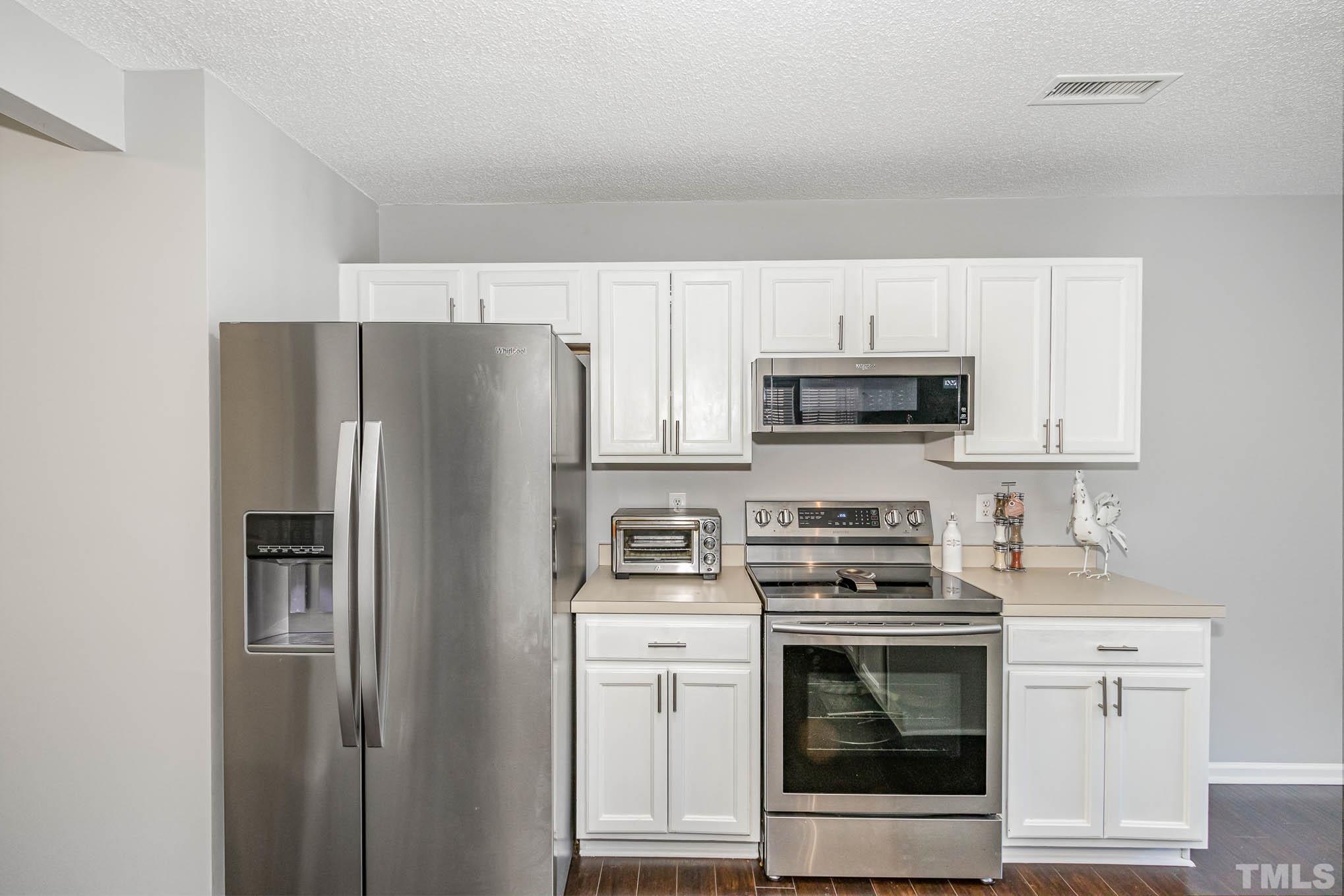 266 Inkster Cove Raleigh, NC 27603 - Photo 10 of 30 a kitchen with stainless steel appliances white cabinets and a stove