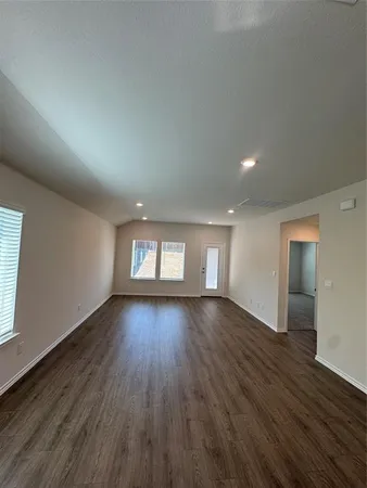 a view of an empty room with wooden floor and window