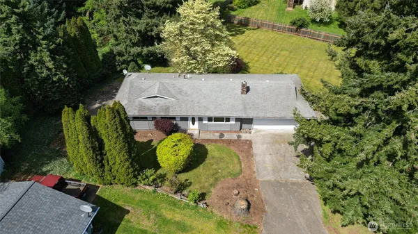 an aerial view of a house with swimming pool and large trees
