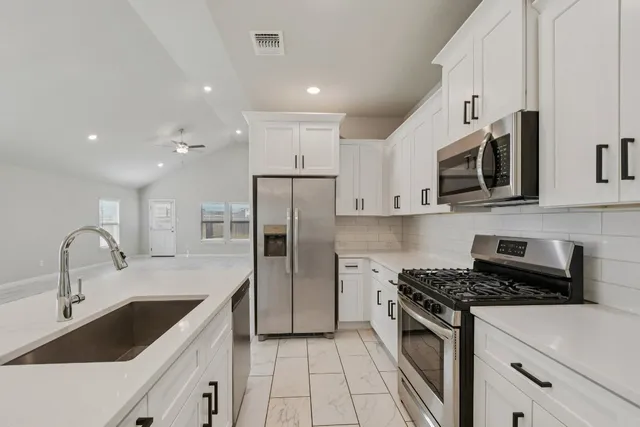 a kitchen with white cabinets and appliances