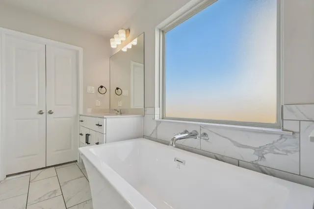 a bathroom with a bathtub a sink and a window