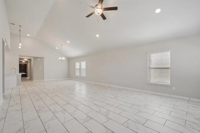 an empty room with windows and ceiling fan