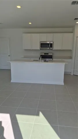 a kitchen with stainless steel appliances a sink a stove a microwave a center island and cabinets