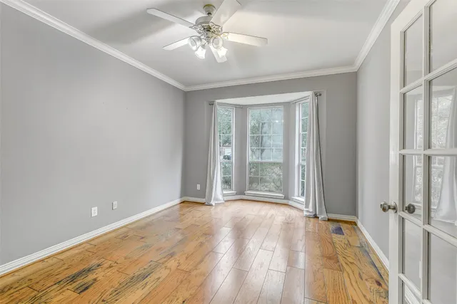 a view of an empty room with wooden floor fireplace and a window