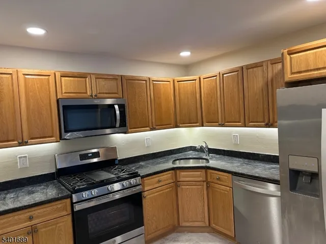 a kitchen with granite countertop a sink stainless steel appliances and cabinets