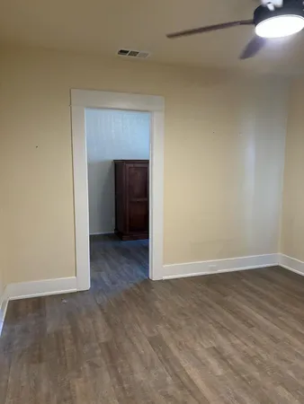 a view of an empty room with wooden floor and a window