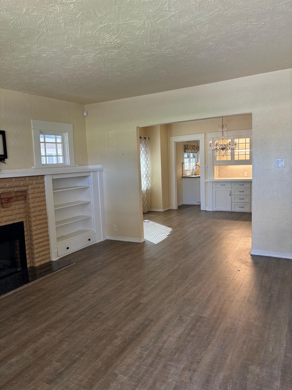 417 Enslen Avenue Modesto, CA 95354 - Photo 3 of 24 an empty room with wooden floor fireplace and windows
