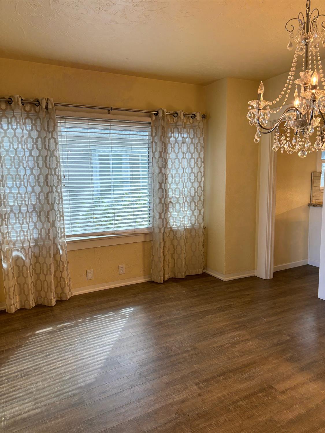417 Enslen Avenue Modesto, CA 95354 - Photo 9 of 24 an empty room with wooden floor and windows