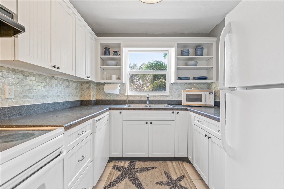 275 Date Palm Road, Unit 307 Vero Beach, FL 32963 - Photo 3 of 36 a kitchen with granite countertop white cabinets and white appliances