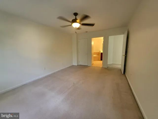 an empty room with a chandelier fan and windows