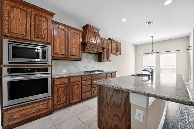 a kitchen with granite countertop a stove sink and microwave