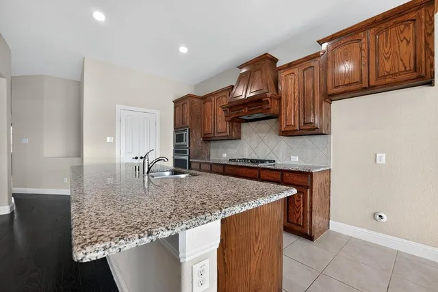 a kitchen with kitchen island granite countertop wooden cabinets a sink and dishwasher