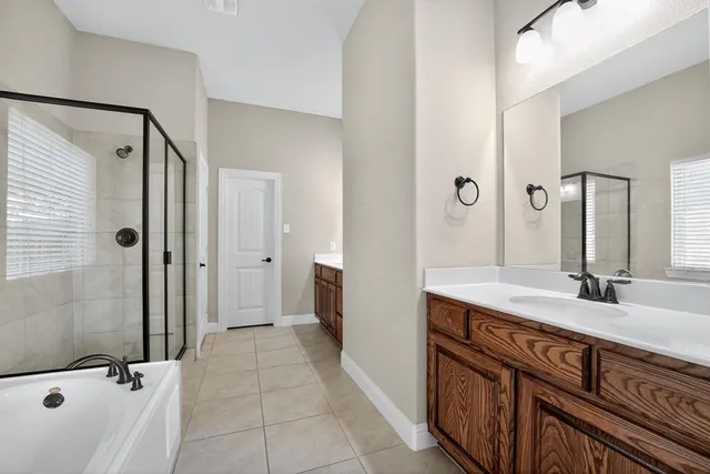 a bathroom with a sink double vanity granite tub shower and a mirror