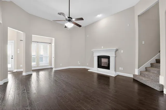a view of an empty room with wooden floor fireplace and a window