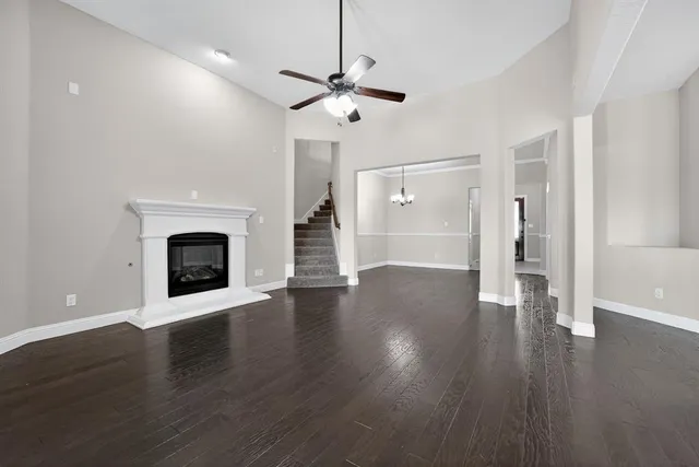 a view of an empty room with wooden floor fireplace and a window