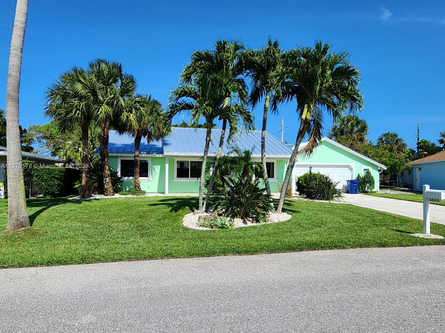 1513 Lance Road Jupiter, FL 33469 - Photo 2 of 33 a front view of a house with a garden and trees
