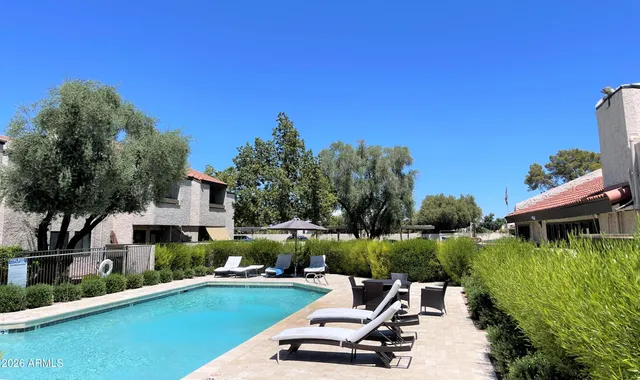 a view of a swimming pool and lounge chairs in back yard