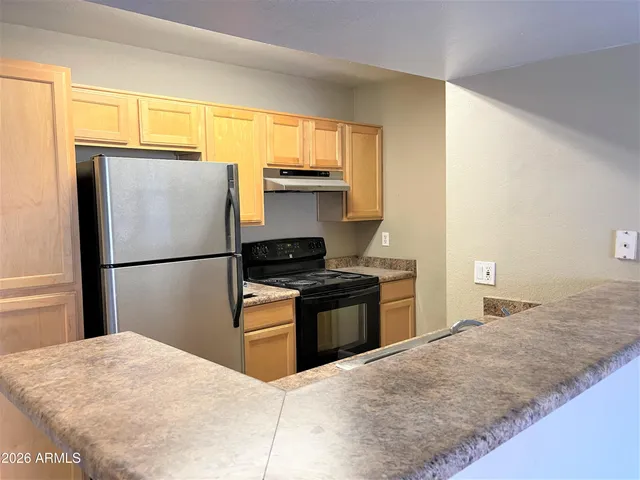 a kitchen with granite countertop a refrigerator stove top oven and sink