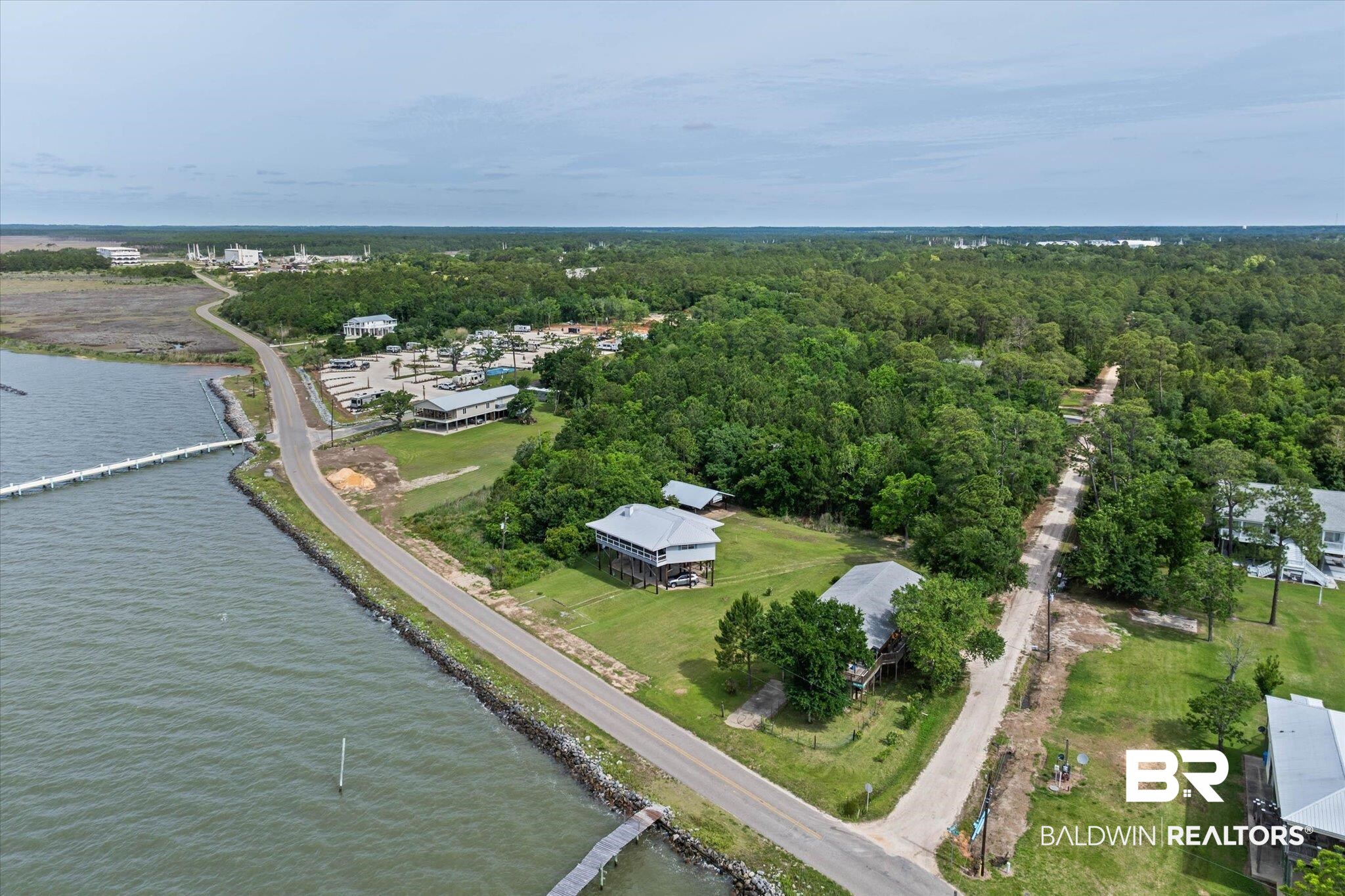 9100 Shell Belt Road Coden, AL 36523 - Photo 24 of 38 Waterfront property featuring an expansive water body, a long pier extending into the water, and a paved road bordering the water