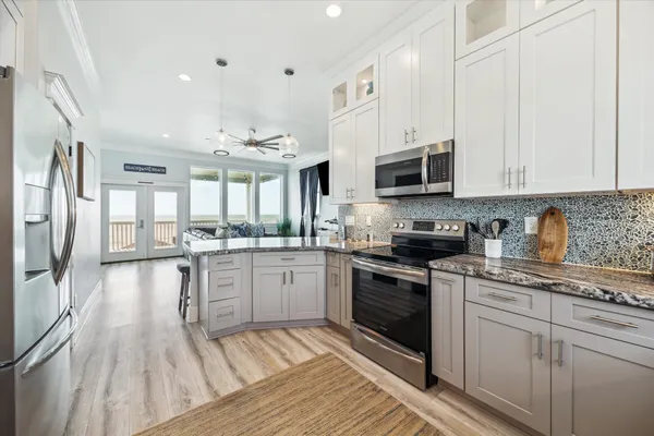 a kitchen with stainless steel appliances granite countertop a stove and white cabinets