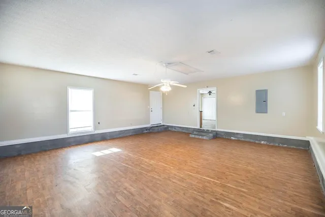 an empty room with wooden floor and windows