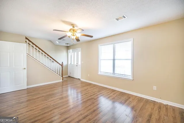 a view of an empty room with wooden floor and a window
