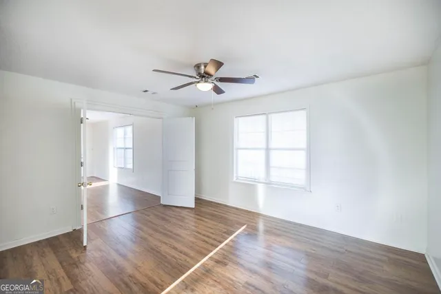 an empty room with wooden floor and windows